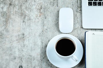 Notebook, laptop, mouse an a cup of tea on wooden desk