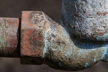 Old steel water tap of an outdated design outdoors, covered in peeling paint, rust marks