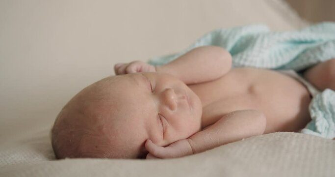 Sleeping newborn baby in plaid. Real time of calm infant child in muslin swaddle lying and sleeping with hands at face