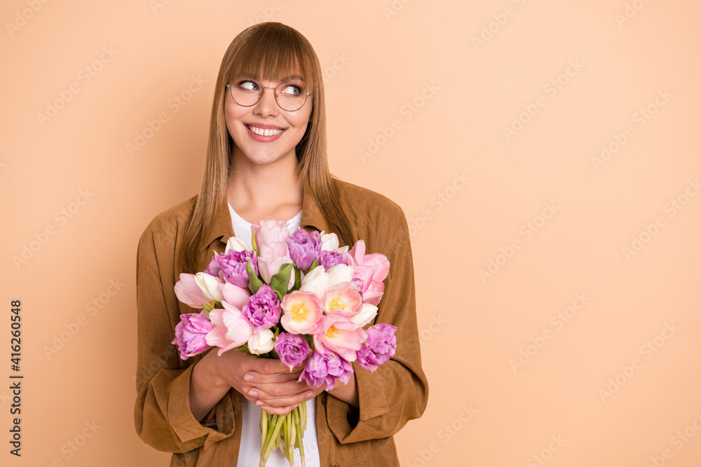 Sticker Photo of dreamy nice happy cheerful lady look empty space hold flowers isolated on pastel beige color background