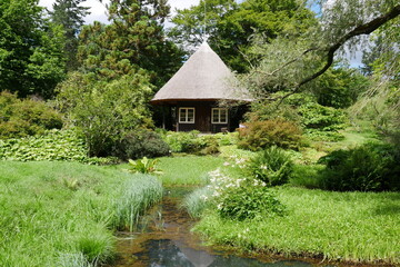 Fototapeta na wymiar Bach und Reetdachhaus im Japangarten im Botanischen Garten Rostock