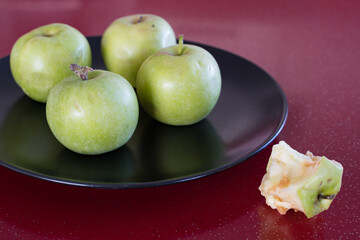 A few green fresh apples and a stub of a eaten apple.