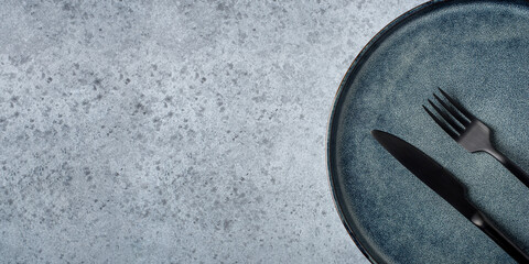 An empty plate and cutlery on a gray table. Top view. Copy space for text.