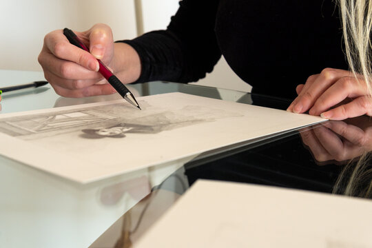Close-up of hands making a figurative drawing in black and white
