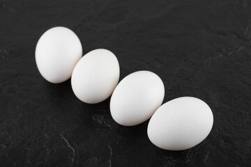 White chicken eggs on a black background