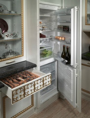 Detail of a fitted drawer on a kitchen cabinet and open fridge 