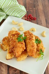 Chicken fingers or chicken strips breaded with cashew and coconut flakes garnish with parsley