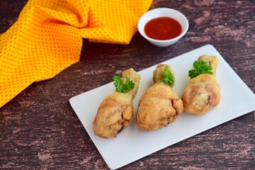 Fried organic chicken legs garnish with parsley and served chili sauce