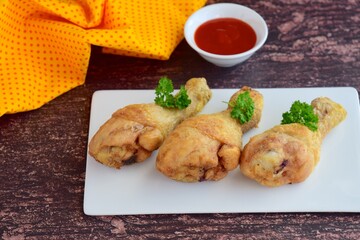 Fried organic chicken legs garnish with parsley and served chili sauce