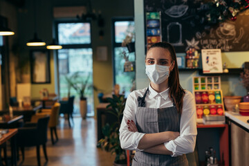Fototapeta na wymiar waitress standing crossed arms in restaurant, She has protective face mask due covid-19