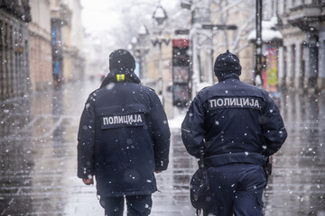Police patrolling and walking trough empty streets on snowy day in Belgrade,Serbia during police...