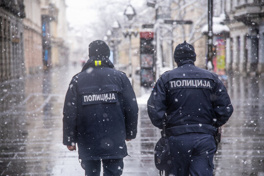 Police patrolling and walking trough empty streets on snowy day in Belgrade,Serbia during police hour due to corona virus covid-19 lockdown
Translation: "Police. "