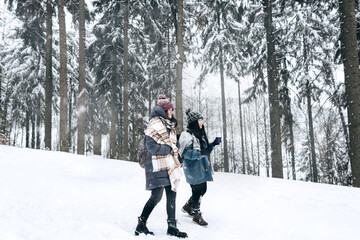 Two active young tourists in warm winter clothes are walking on the background of a beautiful snow-covered landscape.Hiking.Individual adventures.Local travel