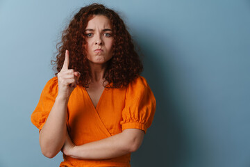 Irritated redhead curly girl wagging her finger at camera