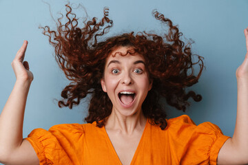 Excited redhead curly girl laughing while making fun with her hair