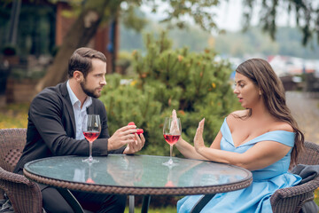 Serious man giving ring and woman refusing