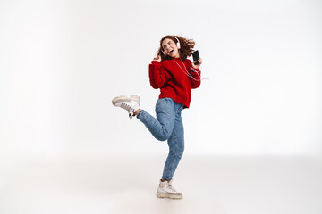 Joyful girl dancing while listening music with cellphone and headphones