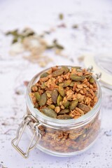 Homemade granola in a jar, made from gluten free oats, pumpkin seeds, sunflower seeds, coconut flakes, maple syrup and coconut oil. 