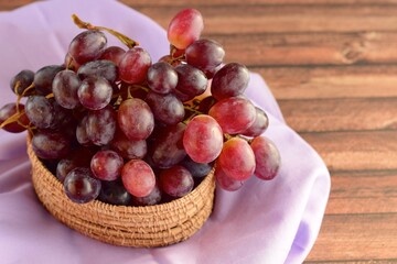 Organic Raw Red Grapes in a Basket on Wooden Background