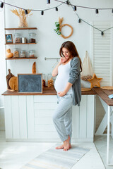 pregnant woman looks at her stomach in the kitchen at home