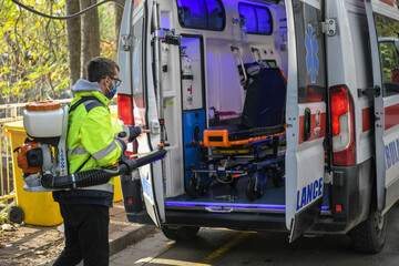 Belgrade, Serbia - 23.11.2020 Paramedics disinfecting the ambulance car who brought coronavirus patients with the motorized backpack atomizer and sprayer. Corona virus, Covid-19 © Dragan