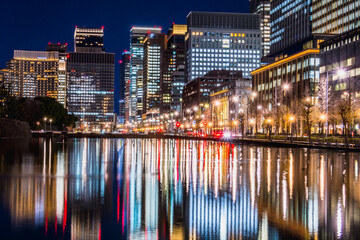 Naklejka premium Night view of Buildings in Marunouchi, Chiyoda District, Tokyo, JAPAN. Imperial Palace, Hibiya moat and Hibiya Street.