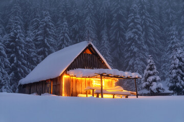 Wooden hut on the lawn covered with snow. The lamps light up the house at the evening time. Winter landscape. Mystical night. Mountains and forests. Wallpaper background.
