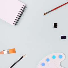 Frame made of tools for painting on a blue pastel background. Creativity concept with copyspace.