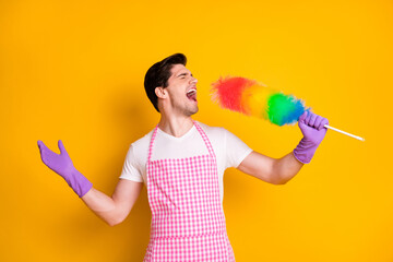 Photo of young crazy funky funny handsome man singing screaming in cleaning brush isolated on yellow color background
