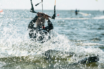 Naklejka premium People swim in the sea on a kiteboard or kitesurfing. Summer sport learning how to kitesurf. Kite surfing on Puck bay in Jastarnia, Poland