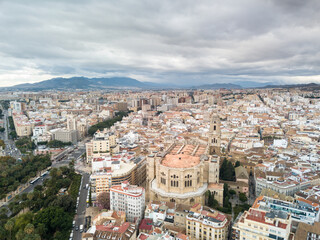 Naklejka premium Aerial drone perspective of Andalusian city Malaga, touristic travel destination on Costa del Sol. Roof top , Cathedral of Malaga, Mountains in background, cloudy day