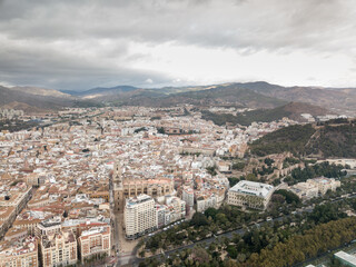 Fototapeta na wymiar Aerial drone perspective of Andalusian city Malaga, touristic travel destination on Costa del Sol. Roof top , Cathedral of Malaga, Mountains in background, cloudy day