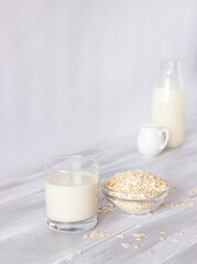 Vegetable oat milk in a glass cup on a light background. Healthy drinks, vegetarianism. Side view. Vertical photo