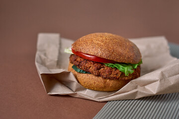 A vegetarian burger made with quinoa, chick peas, rolled oats, crushed onions and garlic, spices on a Whole Wheat Bun with salat, tomatoes and cucumber on the paper bag