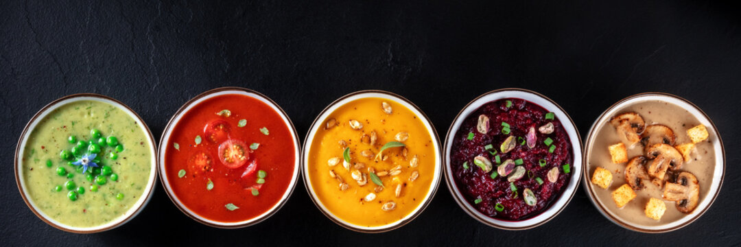 Vegan soup panoramic header with copyspace. Vegetable cream soups, shot from above on a black background