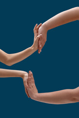 Close up of two women holding or measuring hands, touching each other palms isolated over blue background