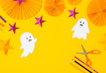Fototapeta premium Halloween paper craft flat lay.Children seasonal art table top view.Kids hand craft concept.Bright halloween background with cutted out ghosts and paper crafts.