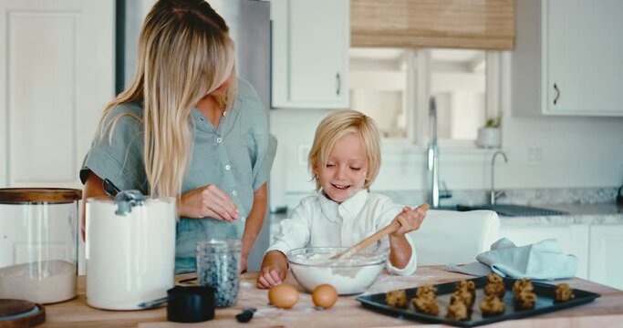 Mother teaching her young boy how to bake cookies in the kitchen, family lifestyle time at home