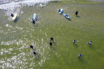Aerial drone view of people surfing in the sea. Summer sport learning how to surf. Surfboarding in baltic sea Jastarnia, Poland