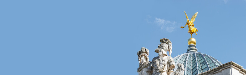 Obraz premium Banner with old statue of golden angel as warrior and defender at the dome top in historical downtown of Dresden, Germany, with copy space and blue sky background.