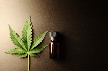 Medicinal cannabis leaf with marijuana oil in bottle on dark  background.