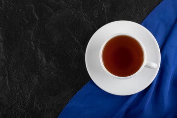 A white cup of hot tea on a black background