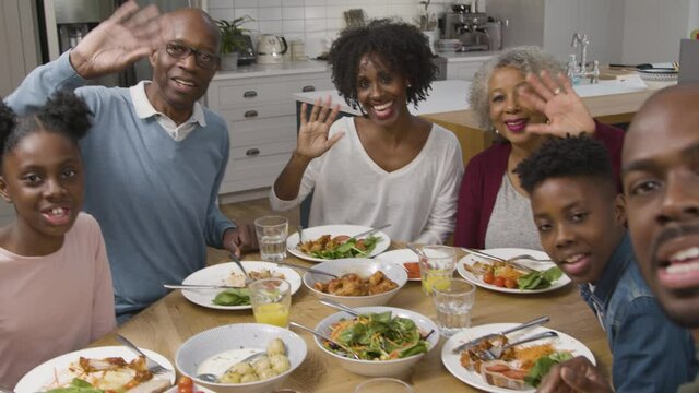 Family Talking Directly to Camera During Video Call at Dinner