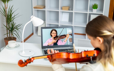 A student learns from a music teacher to play the violin online using a laptop.