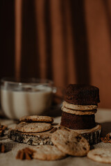 Beautiful creamy coffee in a cup with cookies and brownies carefully placed on the wooden surface with a brown background covered with beams of sunlight