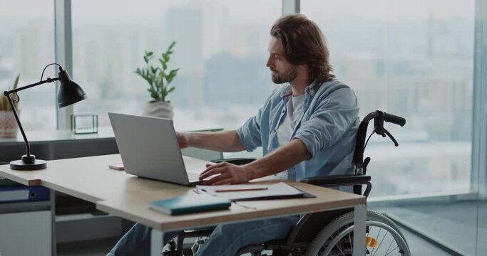 Creative designer male worker using portable computer laptop working in the office. Disabled person corporate employee sitting by pc desk.