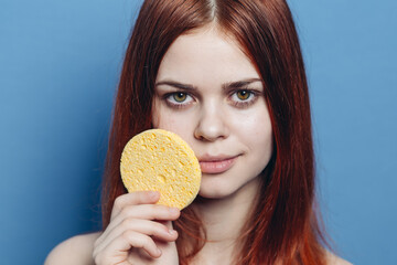 cute redhead woman naked shoulders wipes face with sponge skin care