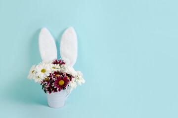 easter spring flowers with rabbit ears on blue background, copy space