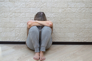 Senior woman with depression stress sad sitting on the floor. The concept of psychological health, emotional anxiety, panic attack, menopause, migraine. The concept of sadness, loneliness, old age.