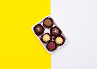 Chocolate cheese truffles, homemade chocolate. Delicious chocolate candies. Group of sweet chocolate truffles on yellow, white background